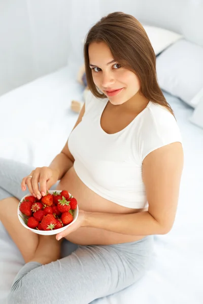 Pregnant Woman Eating Strawberry at home. Healthy Food Concept. — Stock fotografie