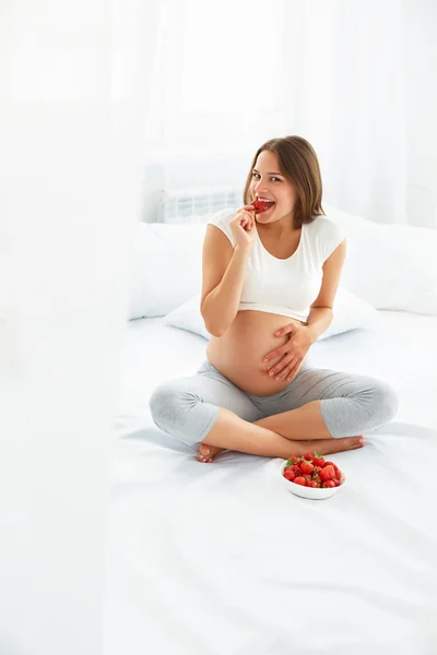 Donna incinta Mangiare fragole a casa. Concetto di cibo sano . — Foto Stock