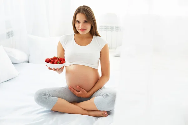 Donna incinta Mangiare fragole a casa. Concetto di cibo sano . — Foto Stock