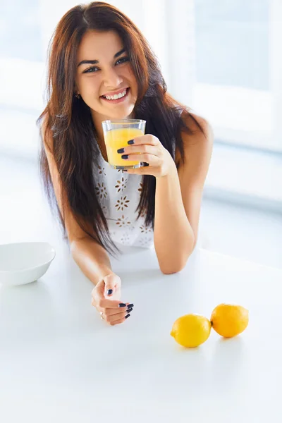 Pequeno-almoço saudável. Mulher bebendo suco de laranja e sorrindo para t — Fotografia de Stock