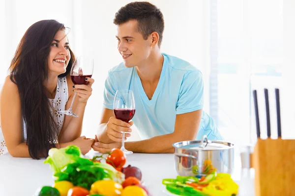 Retrato de um casal tomando um copo de vinho tinto enquanto cozinha — Fotografia de Stock