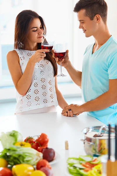Casal clinking seus copos de vinho tinto na cozinha — Fotografia de Stock