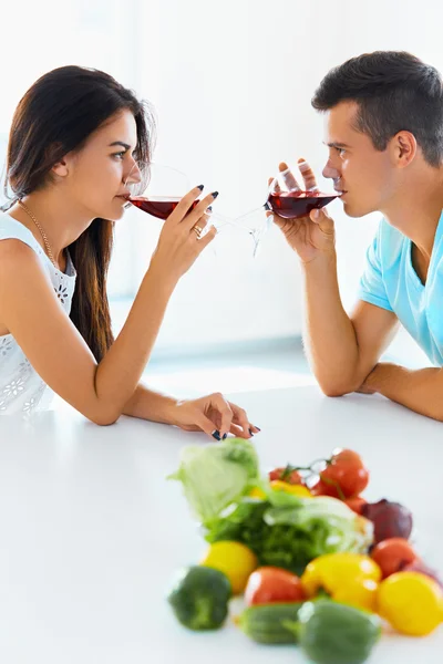 Couple looking at each other while drinking red wine in kitchen — Zdjęcie stockowe