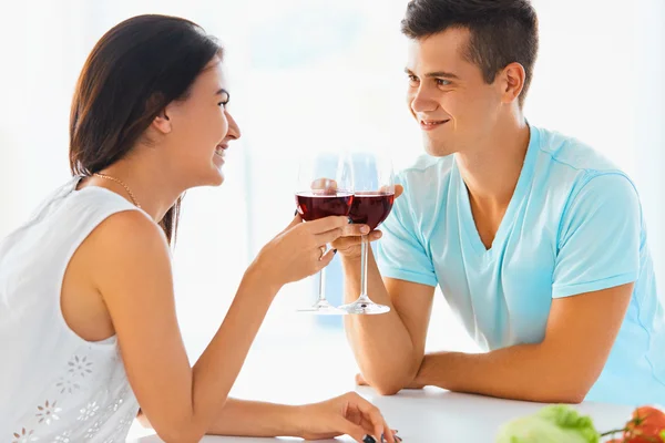 Retrato de casal batendo seus copos de vinho tinto no kit — Fotografia de Stock