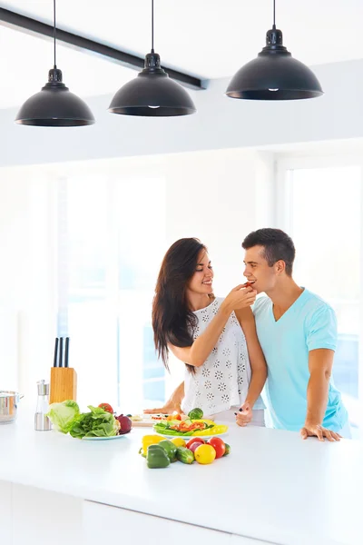 Housewife feeding her husband in their kitchen — Stock Photo, Image