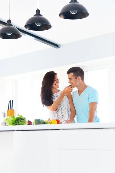 Wife feeding her husband in their kitchen — Stock Fotó