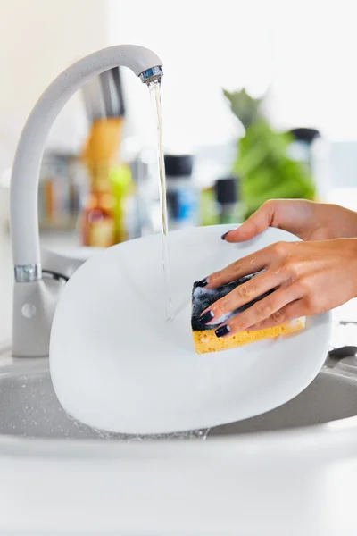 Cerrar las manos de la mujer lavando platos en la cocina — Foto de Stock