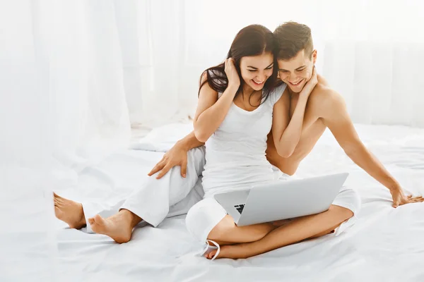 Happy couple with laptop in bedroom — ストック写真