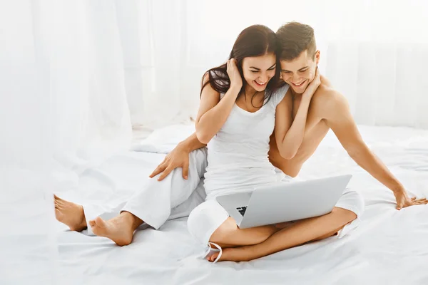 Pareja feliz con portátil en el dormitorio — Foto de Stock