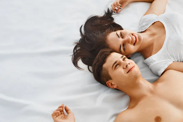 Young couple lying on bed together — 图库照片