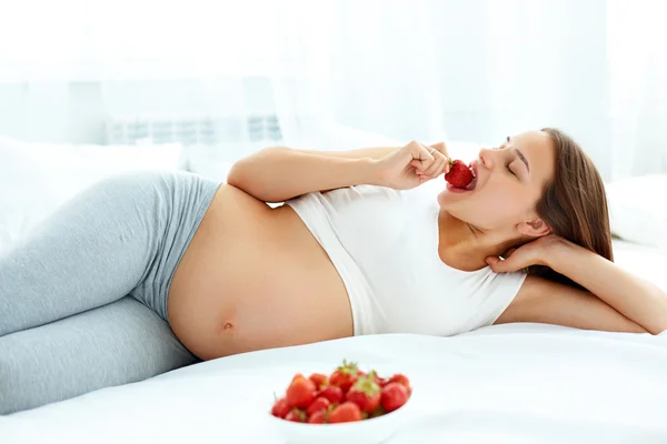 Pregnant Woman Eating Strawberry at home. Healthy Food Concept. Royalty Free Stock Photos