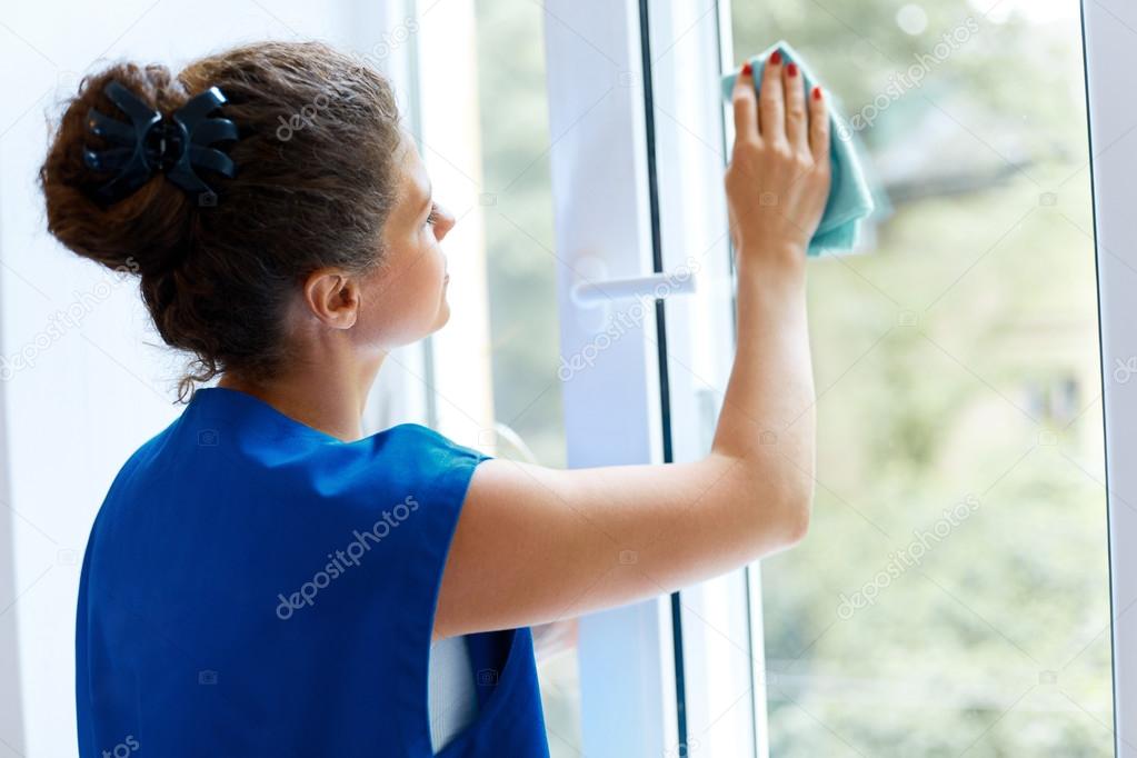 Young Woman cleaning window glass. Cleaning Company Worker