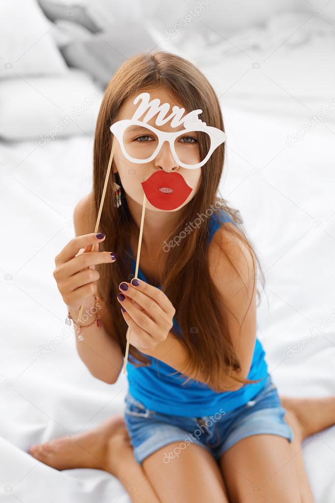 Girl posing with lips and eyeglasses props.