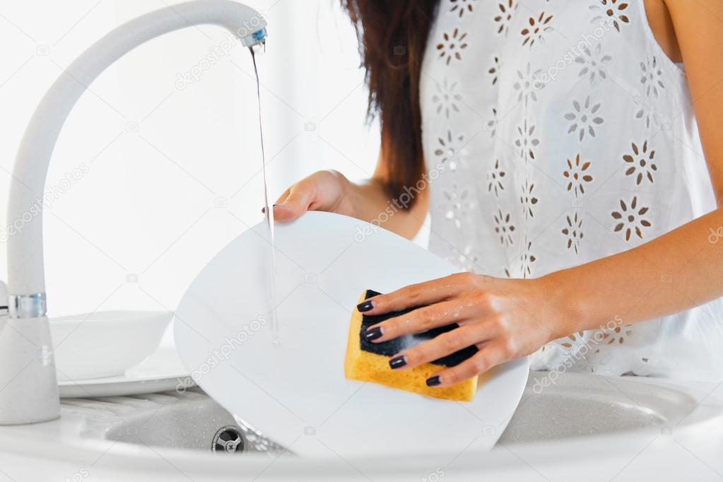 Woman hands with nice manicure washing dishes in the kitchen