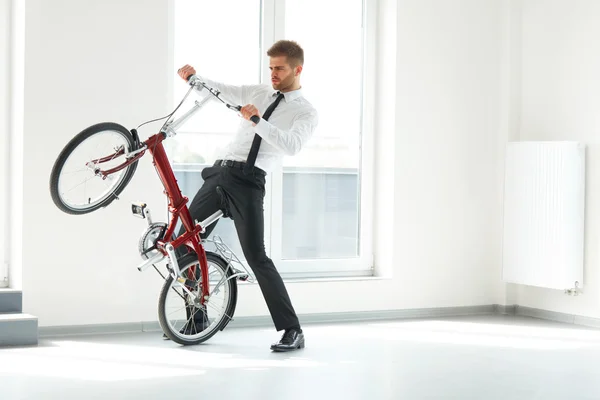 年轻的商人骑他的自行车在办公室。商务人士 — 图库照片