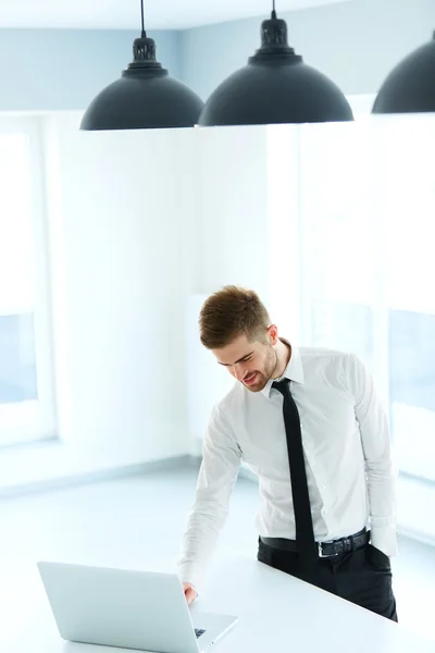 Hombre de negocios guapo trabajando en el ordenador portátil en su oficina — Foto de Stock