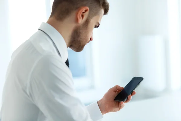 Zakenman leest iets op het scherm van zijn mobiele telefoon — Stockfoto