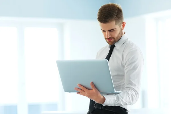 Hombre de negocios guapo trabajando en el ordenador portátil en su oficina —  Fotos de Stock