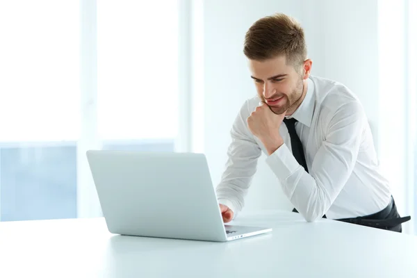 Schöner Geschäftsmann, der in seinem Büro am Laptop arbeitet — Stockfoto