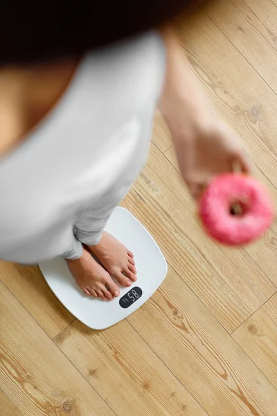 Dieta. Mujer en balanza de pesaje, sosteniendo donut. Comida poco saludable. Ob —  Fotos de Stock