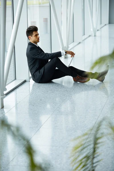 Empresario con portátil cerca de la ventana y pensando en la F —  Fotos de Stock