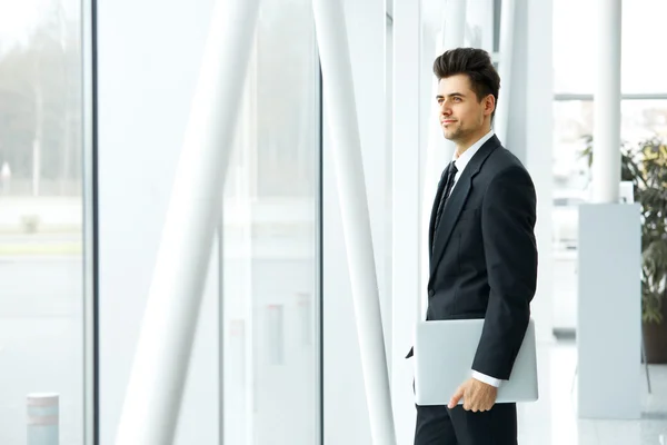 Hombre de negocios con ordenador portátil cerca de la ventana y pensando en el — Foto de Stock