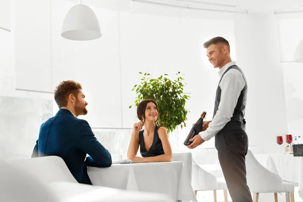 Kellner bringt Weinflasche an verliebtes Paar. romantisches Abendessen. — Stockfoto