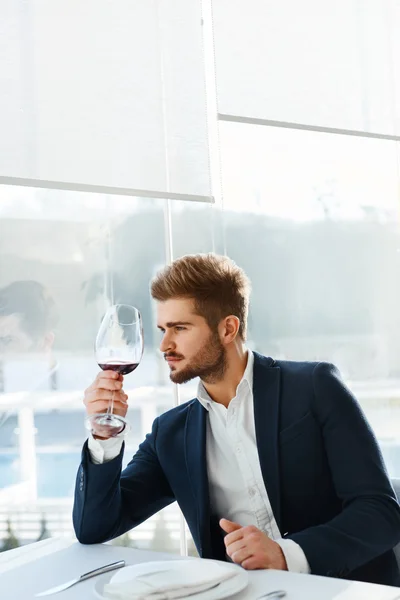 Bebe. Bonito homem bebendo vinho no restaurante. Homem de negócios Su — Fotografia de Stock