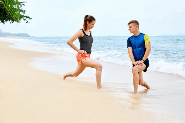 Atletismo. Ajuste pareja estiramiento, ejercicio en la playa. Deportes, F — Foto de Stock