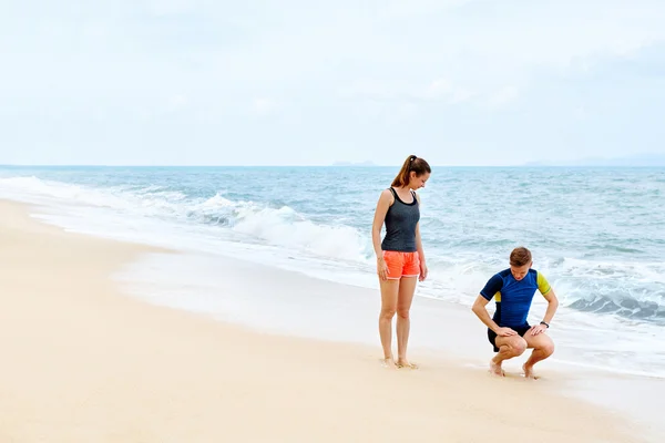Exercices de conditionnement physique. Couple en bonne santé accroupi, faisant de l'exercice sur la plage — Photo