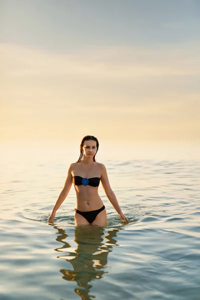 Un estilo de vida saludable. Mujer de pie en el mar al atardecer. Vacaciones de verano — Foto de Stock