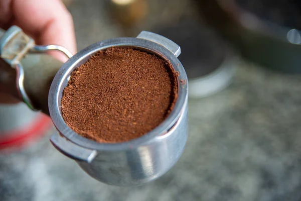 Elinde topraklanmış kahve olan bir espresso makinesi.