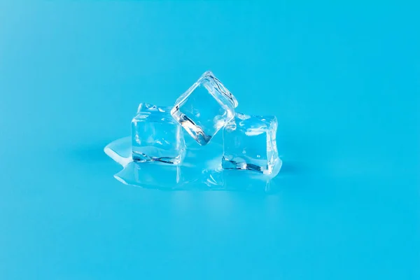 Melting three ice cubes on a blue background, meltwater from melting ice.