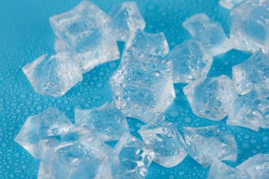 Su damlacıklarındaki mavi arka planda bir sürü buz ve buz var. İçecekler için buz eritiyorum.