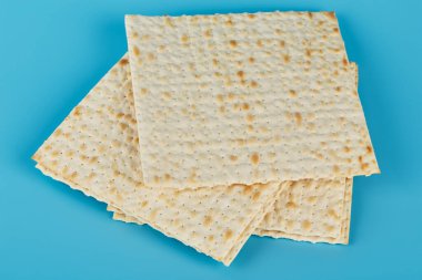 Geleneksel Yahudi bayramı için Matzah, mavi arka planda yatar. Ortadaki matzo 'nun yakın plan fotoğrafı.