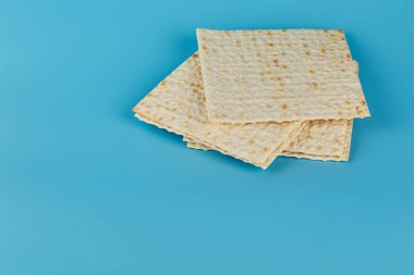 Fısıh bayramı için geleneksel Yahudi matzası mavi arka planda yatar. Boş alan. Yahudi bayramı kavramı.