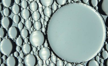 Su yüzeyinde yüzen petrol çemberlerinin soyut makro arka planı. Makro, su üzerindeki baloncukları yakından görüyor. Su makro fotoğraf arkaplanında yağ kabarcıkları