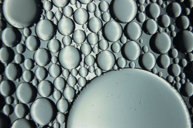 Su yüzeyinde yüzen petrol çemberlerinin soyut makro arka planı. Makro, su üzerindeki baloncukları yakından görüyor. Su makro fotoğraf arkaplanında yağ kabarcıkları