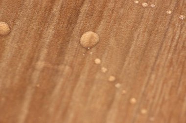 Ahşap zemindeki su damlalarının seçici odak noktası. Tahta üzerinde soyut yağmur damlaları deseni
