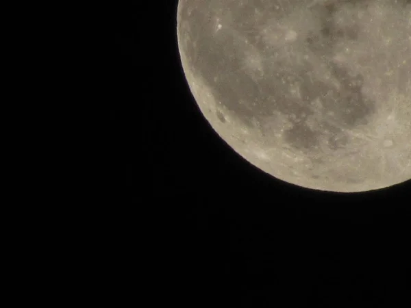 Earth\'s Moon Glowing On Black Background. The Moon close-up on a black night sky shot through a telephoto camera.