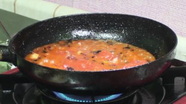 Kızartma tavasında yakın görüşlü domates ve soğan kızartma. Soğanla domatesin sobada ahşap kepçeyle karıştırılması..