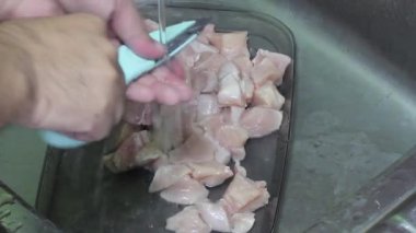 Yüksek açı, tavuk göğsünü keskin bir et makasıyla parçalara ayırıyor. Yemek yapmak için çiğ tavuk filetosunu küçük parçalara ayırıyor..