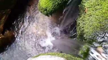 Sudan akan akarsuyun yakın görüntüsü taşların arasından dökülür ve akar.