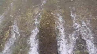 Su barajının asfaltlı yüzeyindeki su akışının en üst drone görüntüsü. Asfaltlı yüzeyde akan beyaz su