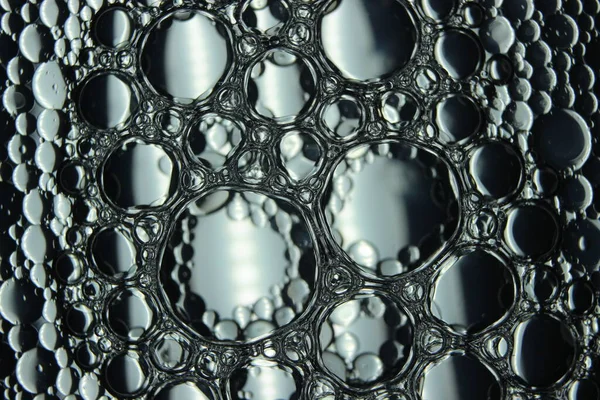 Su yüzeyinde yüzen petrol çemberlerinin soyut makro arka planı. Makro, su üzerindeki baloncukları yakından görüyor. Su makro fotoğraf arkaplanında yağ kabarcıkları