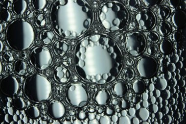 Su yüzeyinde yüzen petrol çemberlerinin soyut makro arka planı. Makro, su üzerindeki baloncukları yakından görüyor. Su makro fotoğraf arkaplanında yağ kabarcıkları