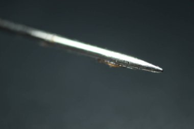 Dikiş iğnesinin makro fotoğrafı. Siyah arkaplan üzerinde izole edilmiş boş göz dirseği ile küçük iğne.