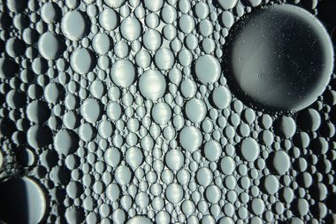 Su yüzeyinde yüzen petrol çemberlerinin soyut makro arka planı. Makro, su üzerindeki baloncukları yakından görüyor. Su makro fotoğraf arkaplanında yağ kabarcıkları