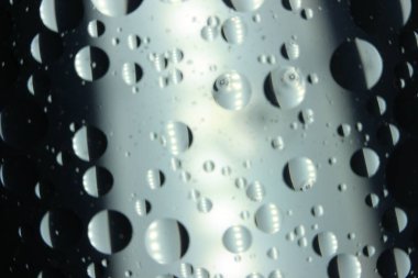 Su yüzeyinde yüzen petrol çemberlerinin soyut makro arka planı. Makro, su üzerindeki baloncukları yakından görüyor. Su makro fotoğraf arkaplanında yağ kabarcıkları