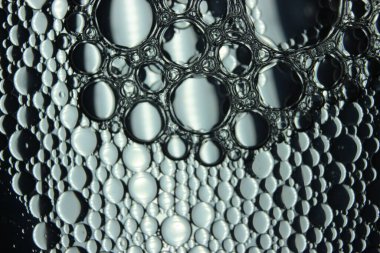 Su yüzeyinde yüzen petrol çemberlerinin soyut makro arka planı. Makro, su üzerindeki baloncukları yakından görüyor. Su makro fotoğraf arkaplanında yağ kabarcıkları